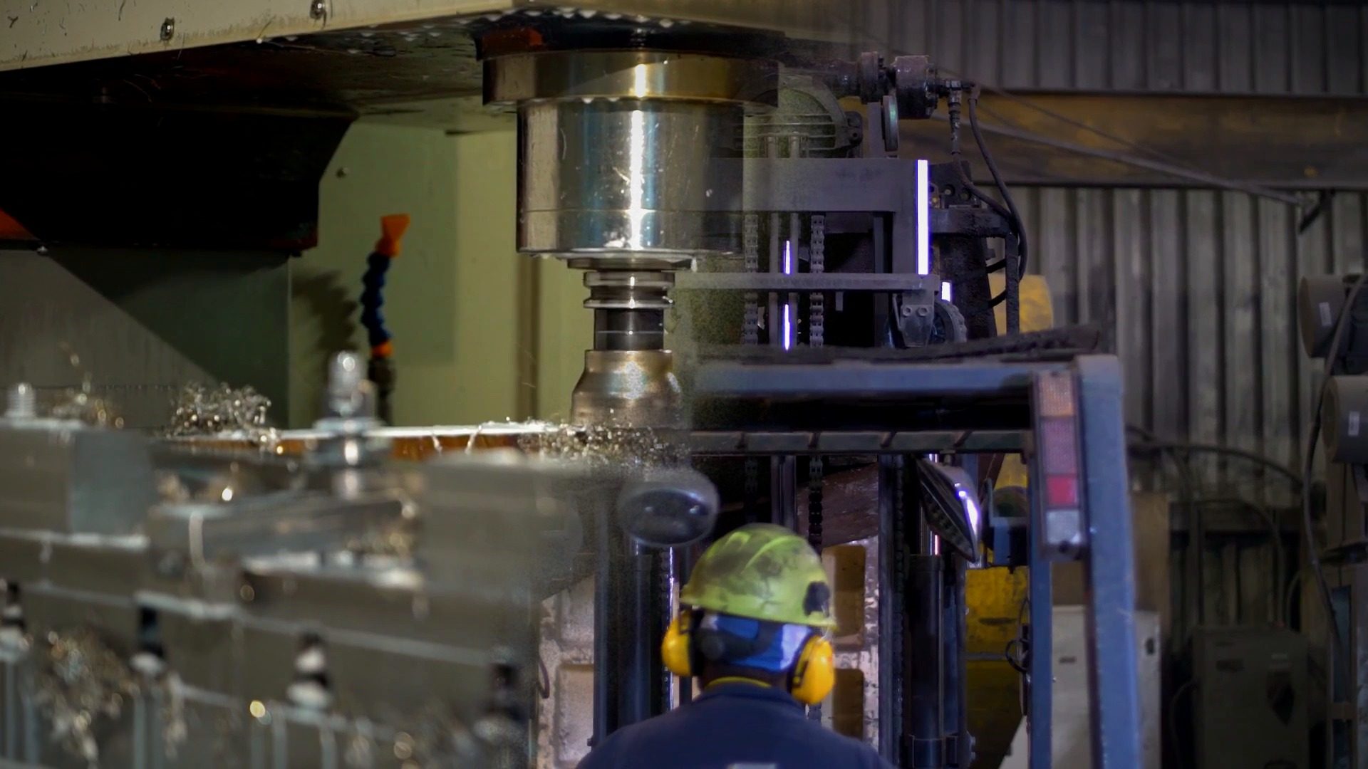 Fresadora CNC cortando metal y montacargas trabajando en una planta de manufactura