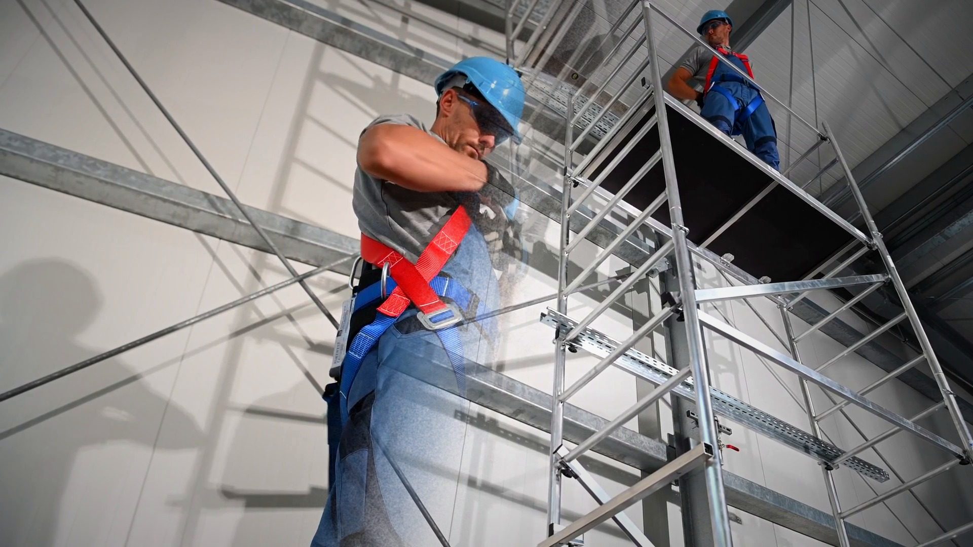 Trabajador con arnés en un andamio dentro de una nave industrial